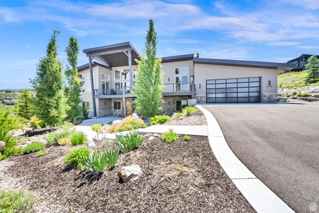 Contemporary home with asphalt driveway, an attached garage, stone siding, and a balcony | Image 99