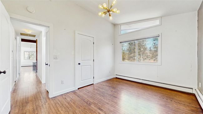 Unfurnished bedroom with baseboards, light wood finished floors, attic access, a notable chandelier, and baseboard heating | Image 18