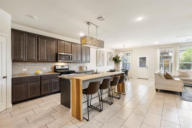 A chef’s dream come true with eat in island & butcher board island extension, stainless steel appliances & granite countertops. | Image 10