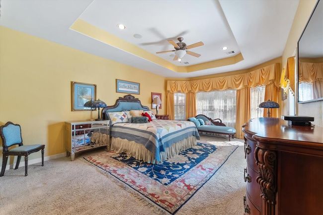 The spacious primary bedroom with raised ceiling, a wall of windows, and en suite bath speaks of luxury | Image 17