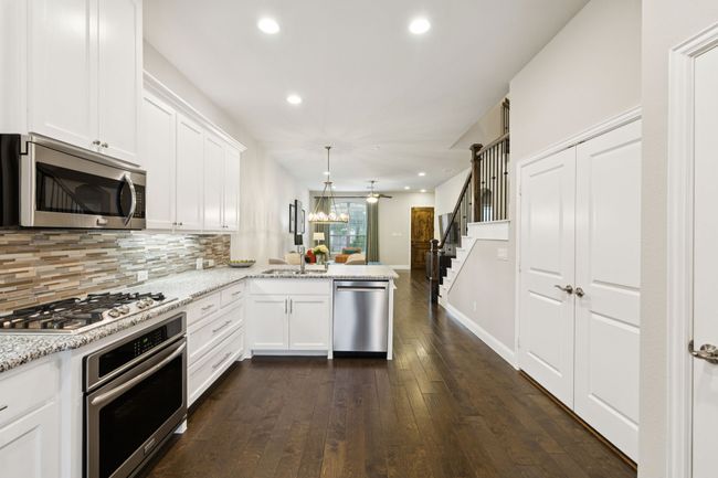 Kitchen featuring stainless steel appliances, a peninsula, dark wood-style floors, white cabinets, and recessed lighting | Image 6