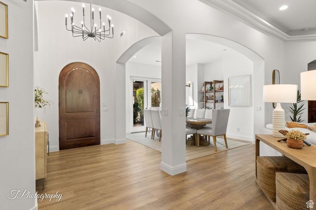 Entrance foyer with a chandelier, light wood finished floors, recessed lighting, arched walkways, and baseboards | Image 11