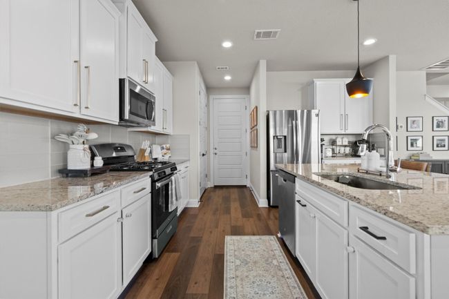 Kitchen with appliances with stainless steel finishes, dark wood-style floors, recessed lighting, white cabinetry, and pendant lighting | Image 13