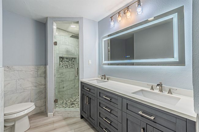 Bathroom with a shower with door, tile walls, hardwood / wood-style floors, vanity, and toilet | Image 22