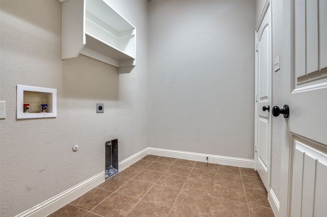Laundry area featuring electric dryer hookup, washer hookup, a textured wall, gas dryer hookup, and tile patterned floors | Image 24
