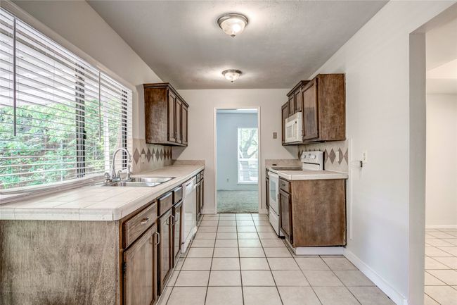 Kitchen featuring white appliances, a sink, light tile patterned flooring, and baseboards | Image 9