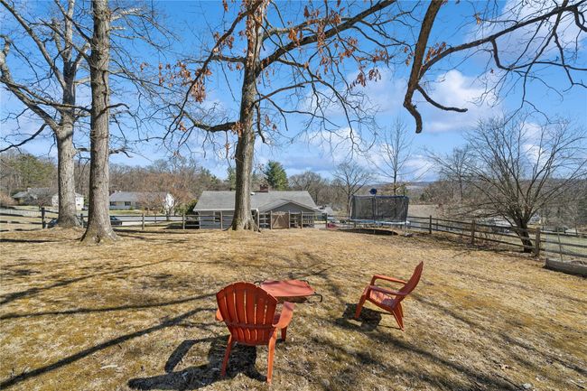 View of yard with a trampoline, an outdoor structure, and fence | Image 9