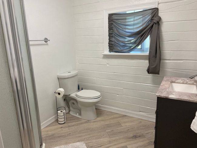 Bathroom with wood-type flooring, wood walls, vanity, and toilet | Image 20