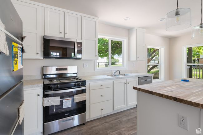 Kitchen with appliances with stainless steel finishes, wood counters, a sink, dark wood-type flooring, and white cabinets | Image 4