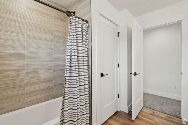 Bathroom featuring shower / tub combo, baseboards, and wood finished floors | Image 26