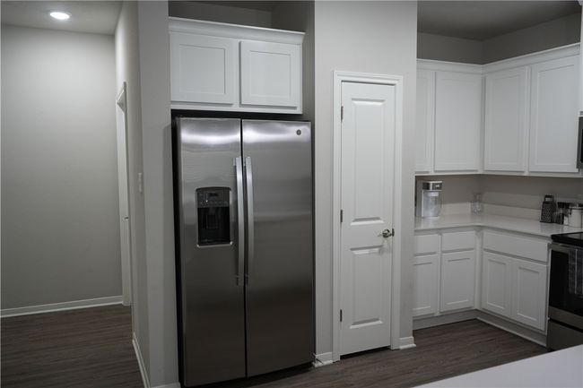 Kitchen with stainless steel appliances, dark wood-style flooring, white cabinets, light countertops, and recessed lighting | Image 7