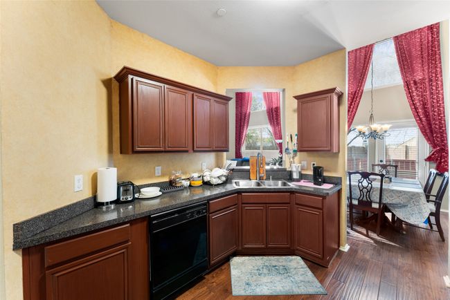 Kitchen featuring a sink, dishwasher, dark countertops, dark wood-type flooring, and an inviting chandelier | Image 11