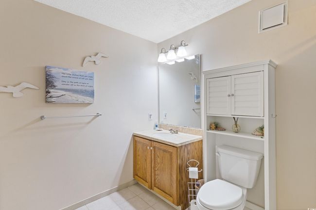Bathroom with tile patterned flooring, vanity, toilet, a textured ceiling, and baseboards | Image 21