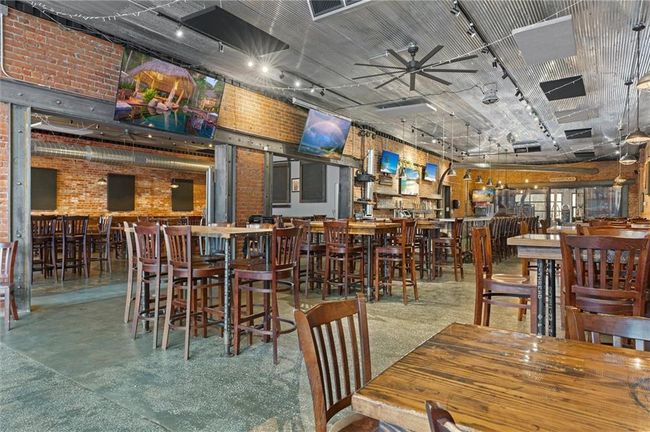 Dining space on bar side featuring brick wall and concrete floors | Image 28
