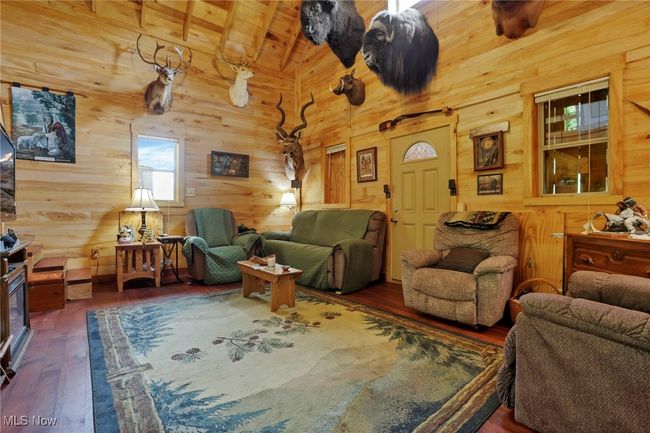 Living area with wooden walls, wood-type flooring, and wooden ceiling | Image 16