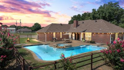 Pool at dusk featuring a patio, a yard, and an in ground hot tub | Image 1