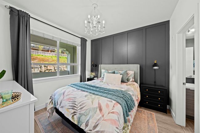 Bedroom featuring light wood finished floors, a decorative wall, baseboards, and a notable chandelier | Image 14