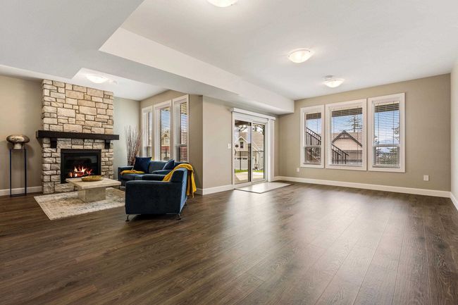 Living room featuring a stone fireplace, dark wood-style floors, and baseboards | Image 32