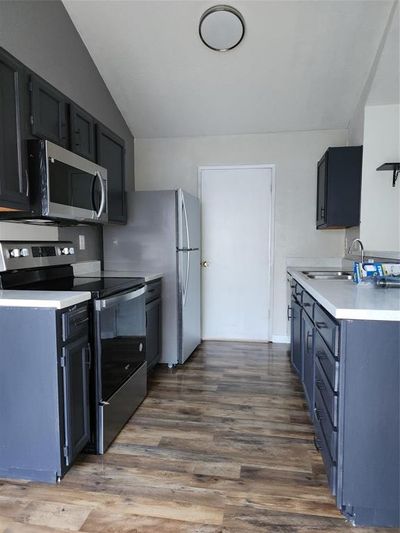 Kitchen with stainless steel appliances, hardwood / wood-style floors, sink, and lofted ceiling | Image 2