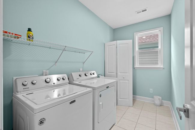 Laundry area featuring baseboards, light tile patterned floors, visible vents, cabinet space, and washer and dryer | Image 17