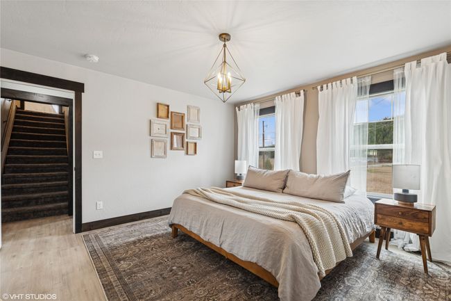 Bedroom with baseboards, multiple windows, a chandelier, and wood finished floors | Image 25