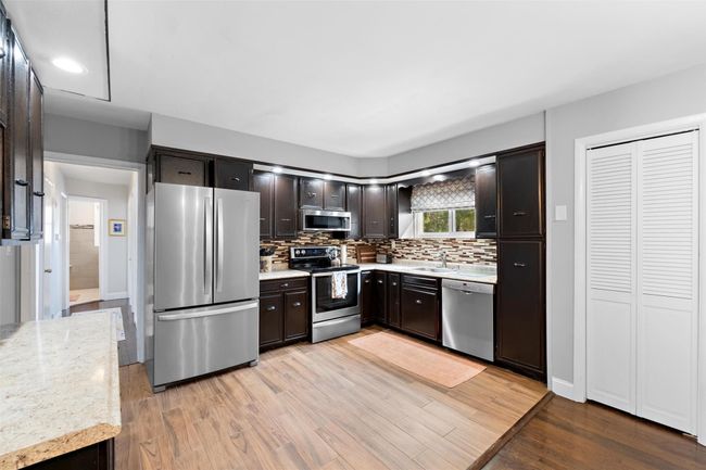 Kitchen with stainless steel appliances, a sink, light wood finished floors, and dark brown cabinets | Image 15