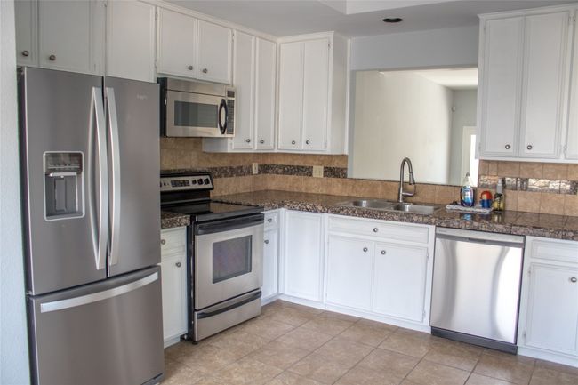 Kitchen with white cabinets, stainless steel appliances, and a sink | Image 8
