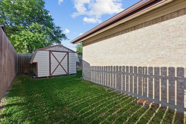 View of yard featuring a fenced backyard, an outdoor structure, and a storage shed | Image 33