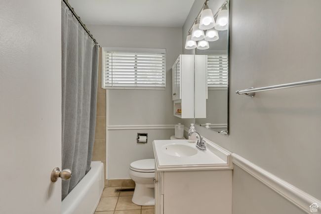 Bathroom with shower / bath combo, vanity, tile patterned flooring, and toilet | Image 11