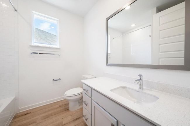Full bath with vanity, wood finished floors, toilet, baseboards, and tub / shower combination | Image 17