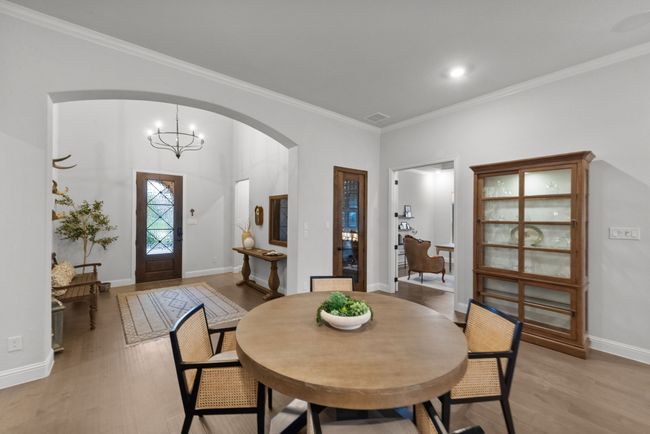 Dining room with arched walkway, light wood flooring, and extensive crown molding | Image 7