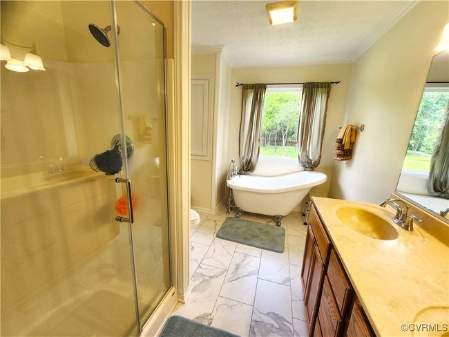 Full bath featuring marble look tiles, double vanity, a stall shower, a freestanding bath, and ornamental molding | Image 17