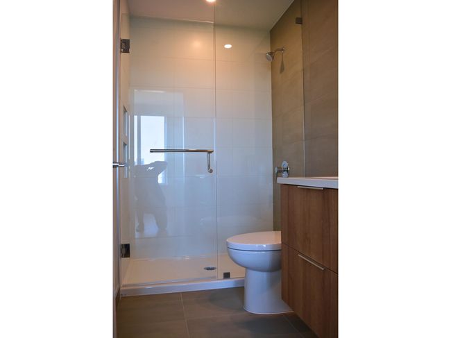 Bathroom featuring tile walls, toilet, tile patterned floors, and a stall shower | Image 14