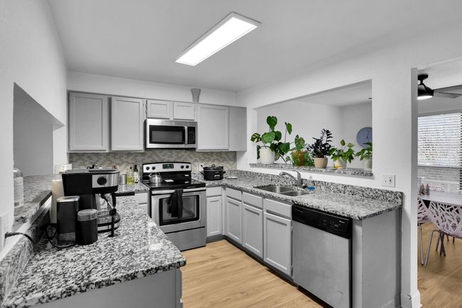 Kitchen featuring appliances with stainless steel finishes, light wood-style flooring, tasteful backsplash, gray cabinets, and light stone counters | Image 14
