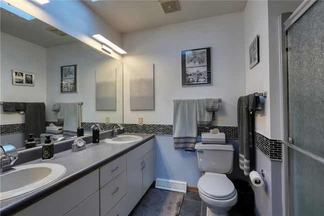 Notice the double sinks for added convenience and the walk-in shower unit. This ensuite bath also features a skylight. | Image 14