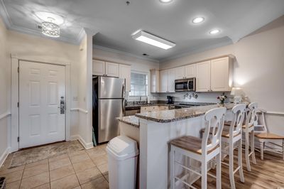 Kitchen featuring dark stone countertops, appliances with stainless steel finishes, kitchen peninsula, and ornamental molding | Image 2