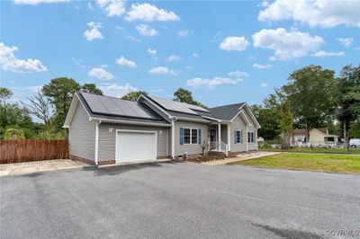 Single story home with a front lawn, solar panels, and a garage | Image 3