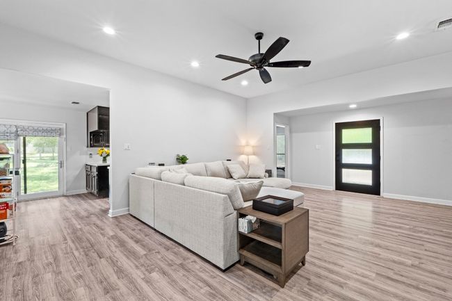 Living area with light wood-style floors, ceiling fan, baseboards, visible vents, and recessed lighting | Image 6