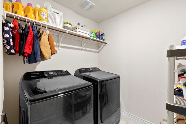 Washroom with light tile patterned floors, laundry area, washing machine and dryer, baseboards, and visible vents | Image 26