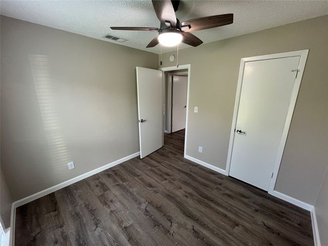 Unfurnished bedroom with dark wood-style floors, a textured ceiling, baseboards, and ceiling fan | Image 15