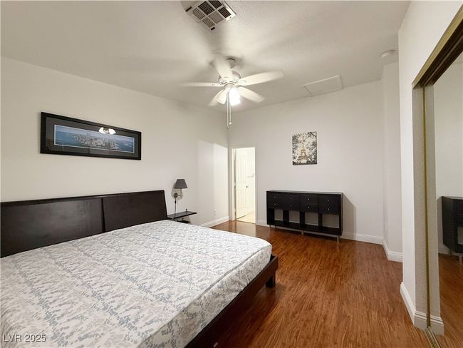 Bedroom featuring attic access, wood finished floors, visible vents, and baseboards | Image 26