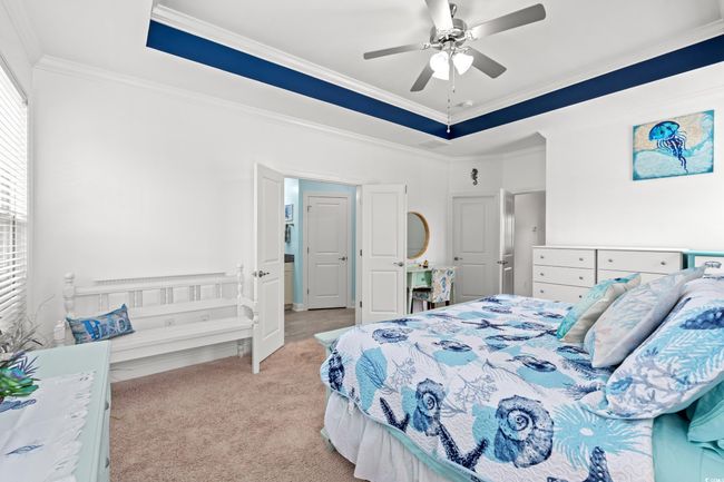 Bedroom featuring crown molding, light carpet, a raised ceiling, and ceiling fan | Image 18