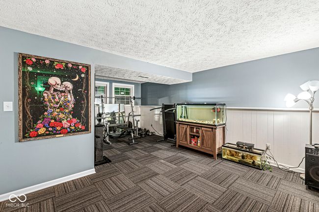 workout area featuring a textured ceiling, carpet flooring, and a wainscoted wall | Image 20