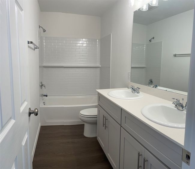 Bathroom with double vanity, toilet, shower combination, and wood finished floors | Image 19