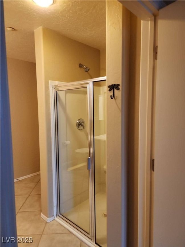 Bathroom featuring a textured ceiling, a shower stall, tile patterned floors, and baseboards | Image 21