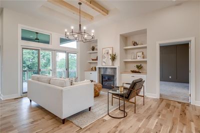 Living room with a notable chandelier, light hardwood / wood-style floors, a fireplace, and built in features | Image 3