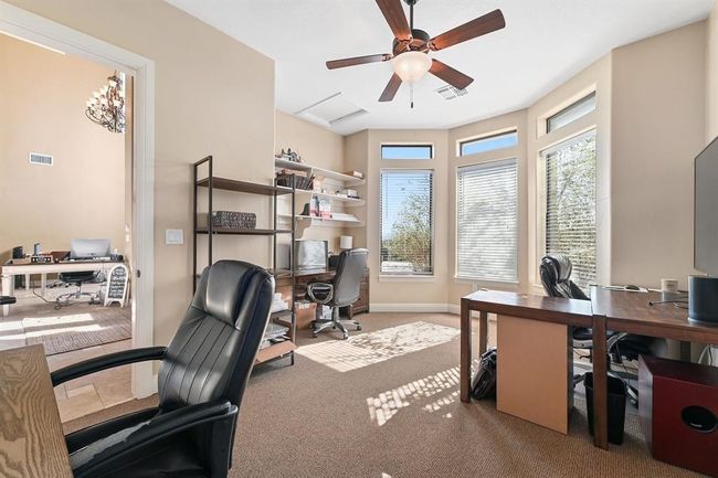 Carpeted home office featuring baseboards, visible vents, and a ceiling fan | Image 14