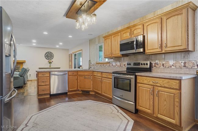 Kitchen with a sink, appliances with stainless steel finishes, light countertops, dark wood-style floors, and a peninsula | Image 18