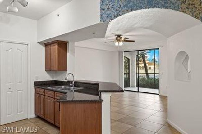 Kitchen with ceiling fan, brown cabinetry, a peninsula, a sink, and dark countertops | Image 13