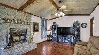 Living area featuring a rock wood burning fire place | Image 2